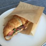 Lobster Croissant in eco takeaway paper bag form if you care brand on a plate