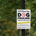 no dog fouling sign in a park with a tree on the background